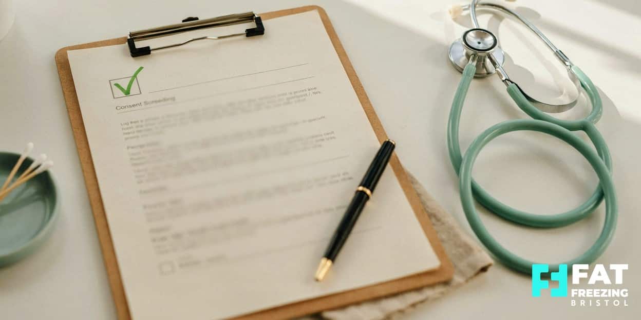 Still-life of a medical screening consent clipboard with a green-ticked checkbox, a fountain pen and a blurred stethoscope on a pale desk, representing the thorough pre-treatment screening essential for safe fat freezing