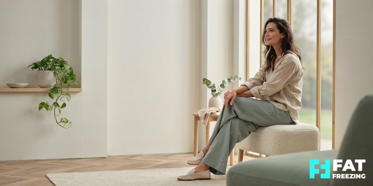 A calm, modern aesthetics clinic with soft natural light and a relaxed person looking thoughtfully out of a window