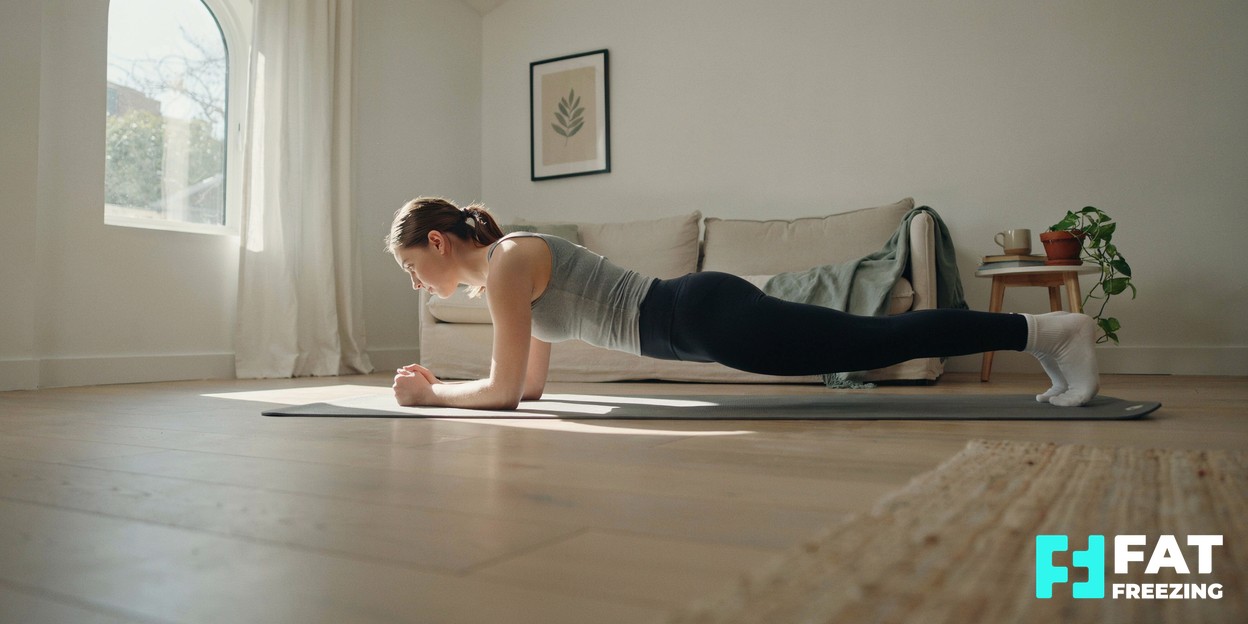 A person doing a bodyweight plank exercise on a yoga mat in a bright, airy living room with soft natural light coming through a window